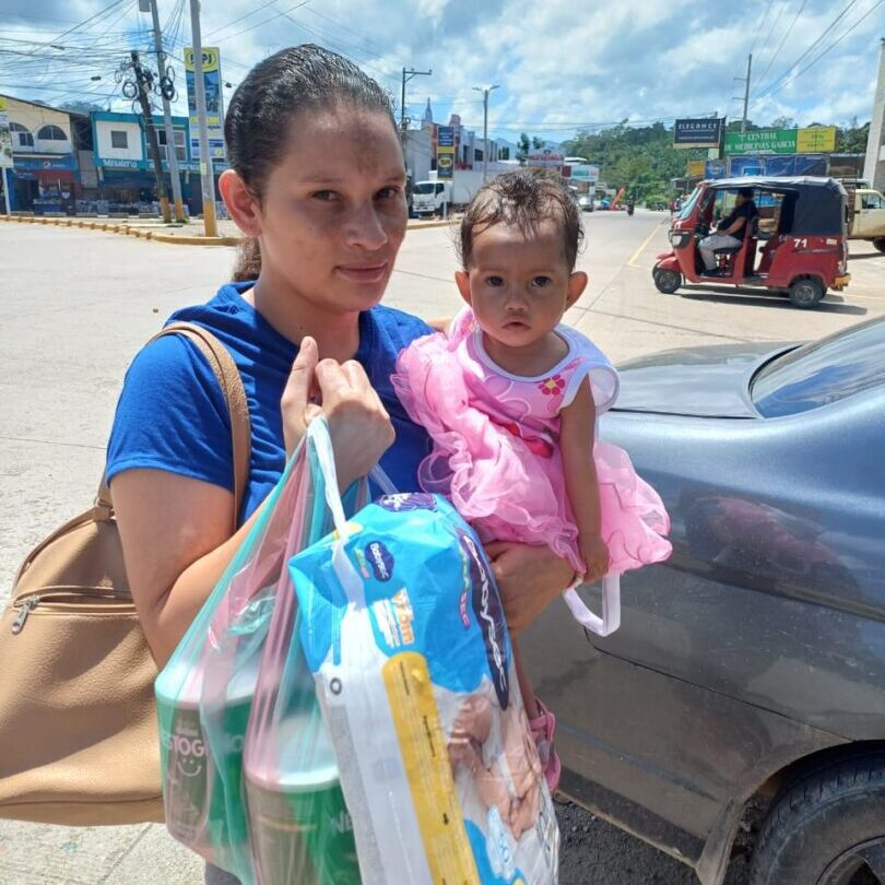 Woman holding toddler and shopping bags